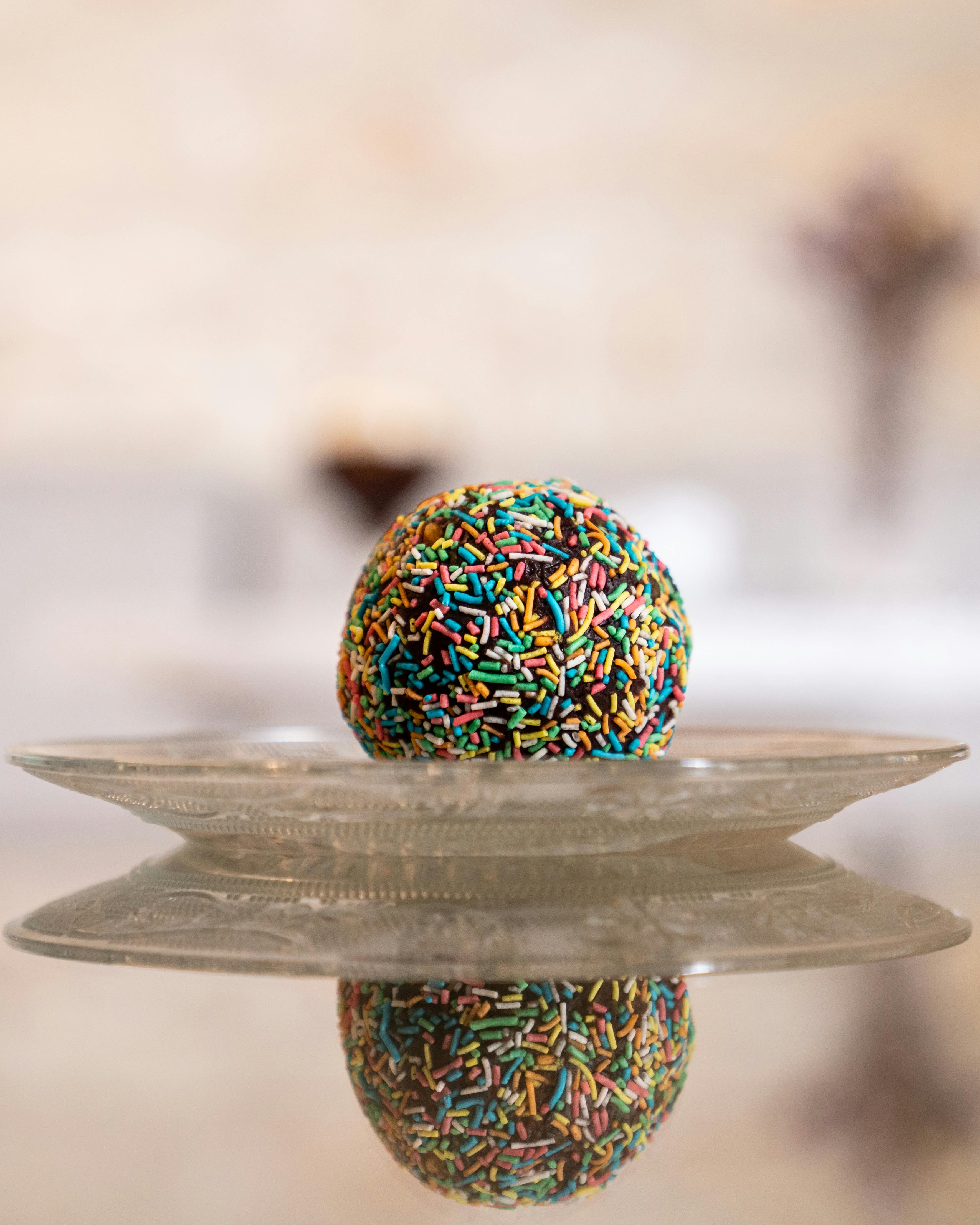 a chocolate ball with sprinkles on top of a glass plate