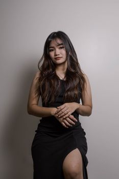 Stylish portrait of a young woman wearing a black dress in a studio setting.