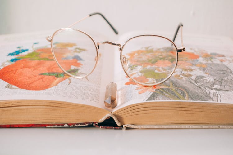 Clsoe-up Of Eyeglasses Lying On An Opened Book With Illustrations 