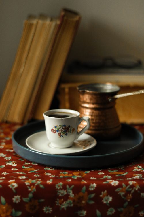 Free Charming coffee scene with a floral cup and traditional pot against book backdrop. Ideal for cozy settings. Stock Photo