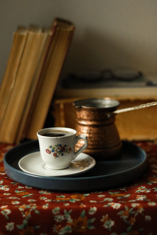 Free Classic coffee scene with a copper pot, floral cup, and vintage books, creating a warm, cozy ambiance. Stock Photo
