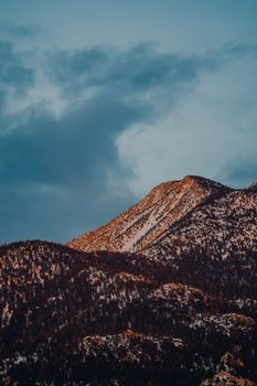 A breathtaking view of a snowcapped mountain under a dramatic sky at sunset.