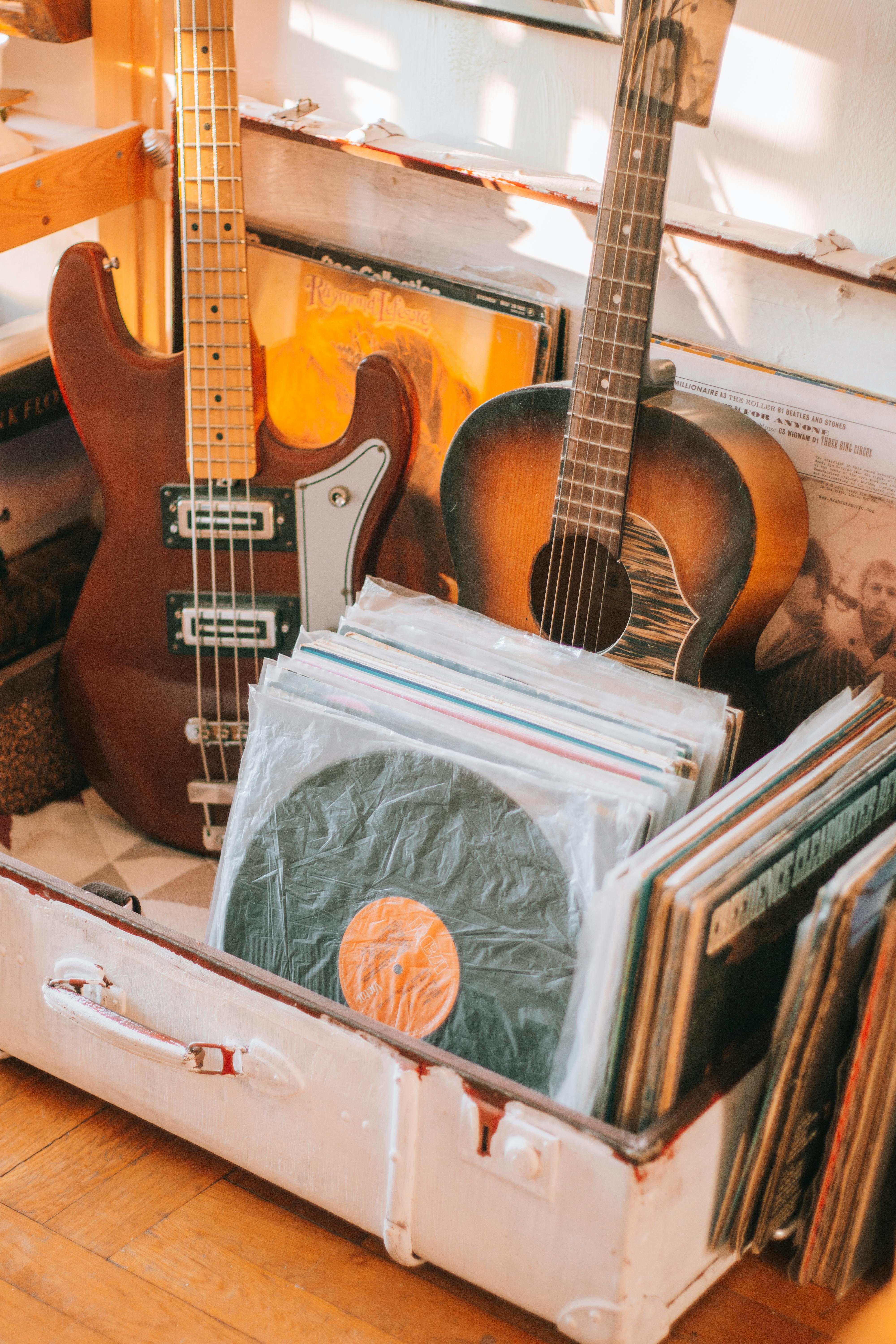 A cozy close-up of a vintage guitar and vinyl collection in a suitcase, evoking nostalgia.