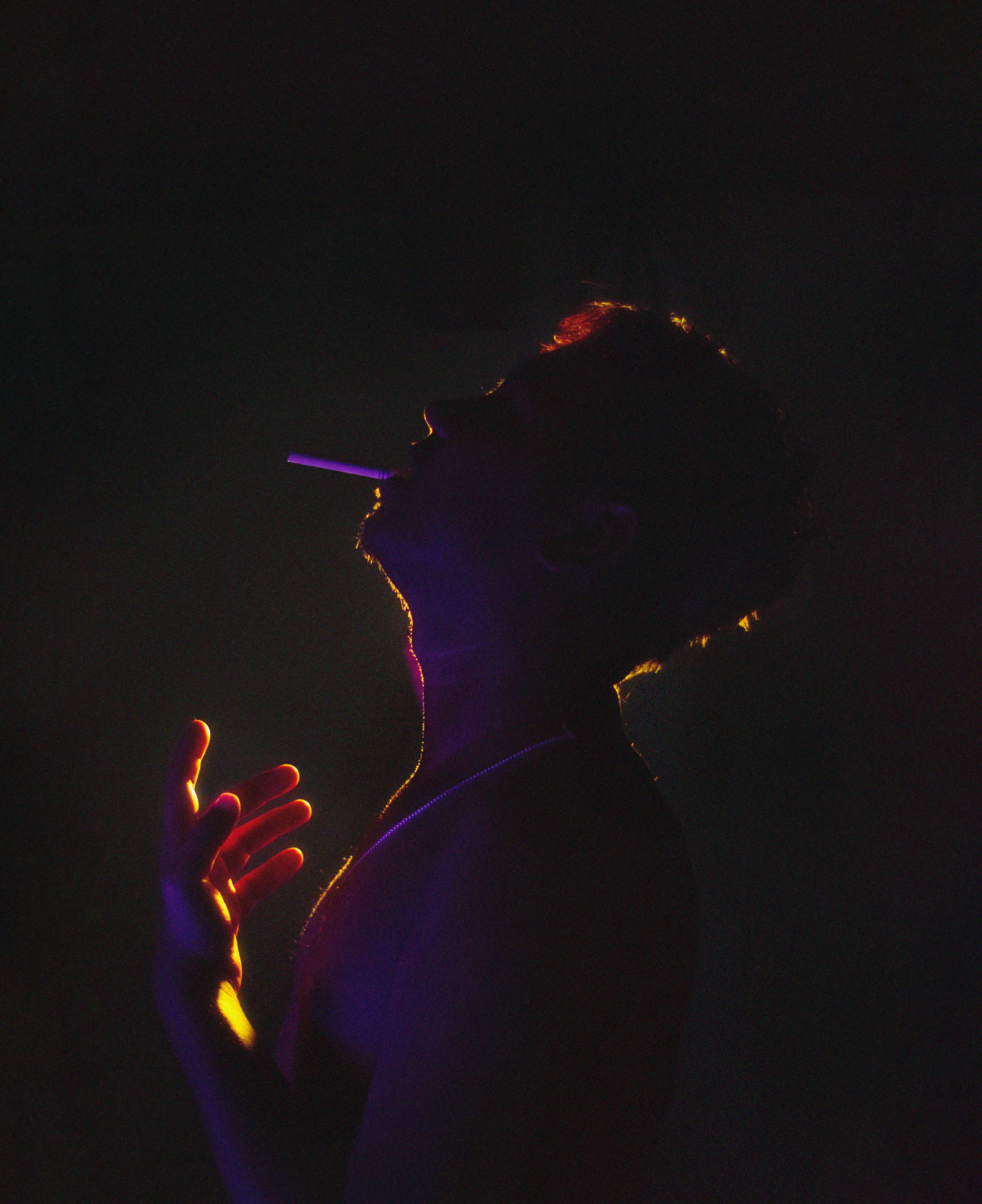 a man smoking a cigarette in the dark