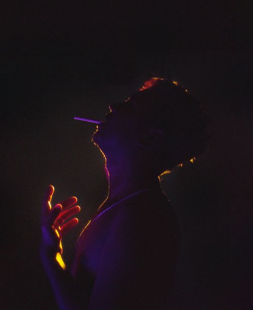 Free Artistic silhouette of a man smoking, highlighted by vibrant lighting, creating a moody and abstract ambiance. Stock Photo