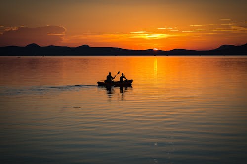 2 Person on Boat Sailing in Clear Water during Sunset