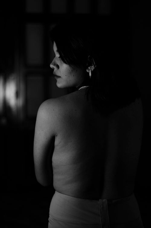 Free Black and white artistic photo of a shirtless woman from behind, in dramatic lighting. Stock Photo