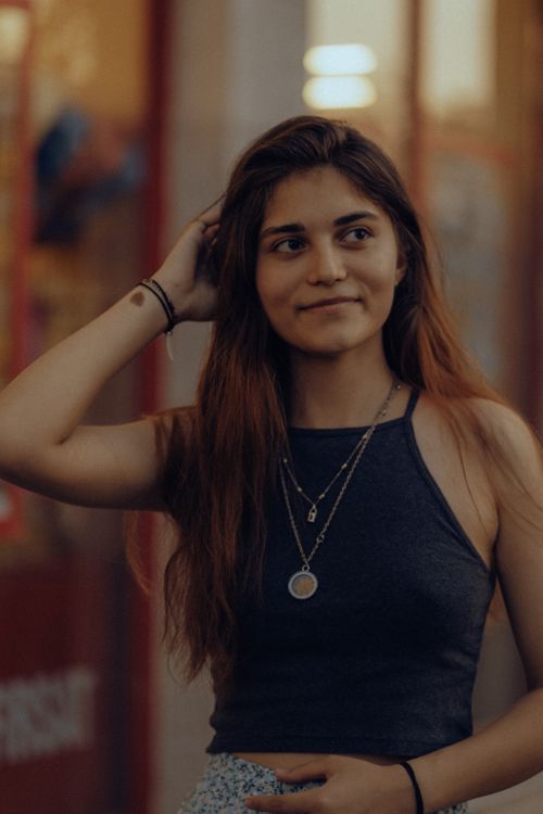 Free Portrait of a young smiling brunette woman outdoors in Fethiye, Türkiye, wearing a trendy tank top and jewelry. Stock Photo