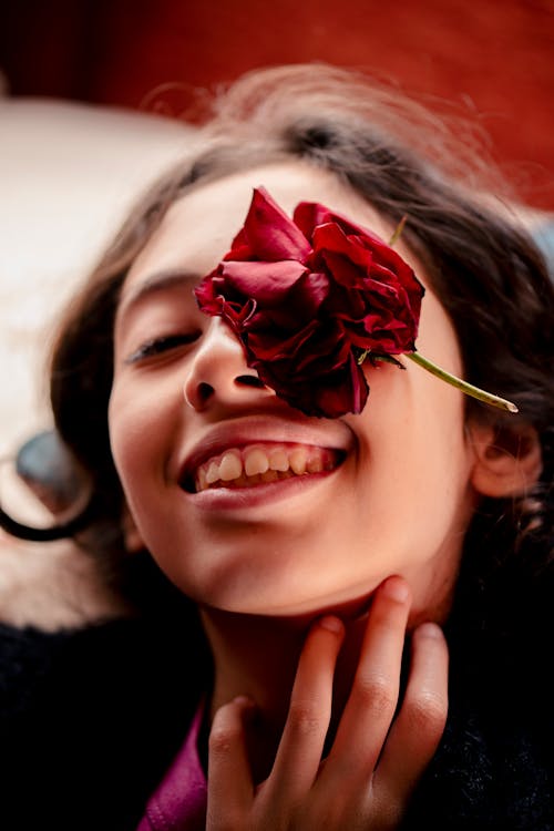 Young Woman with a Flower Head on Her Face Smiling 