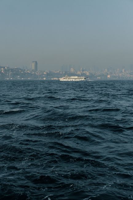A scenic view of a ferry sailing on the Bosphorus with İstanbul skyline in the background.