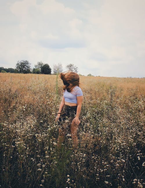 Photo of a Woman with Flowing Hair Standing in a Field 