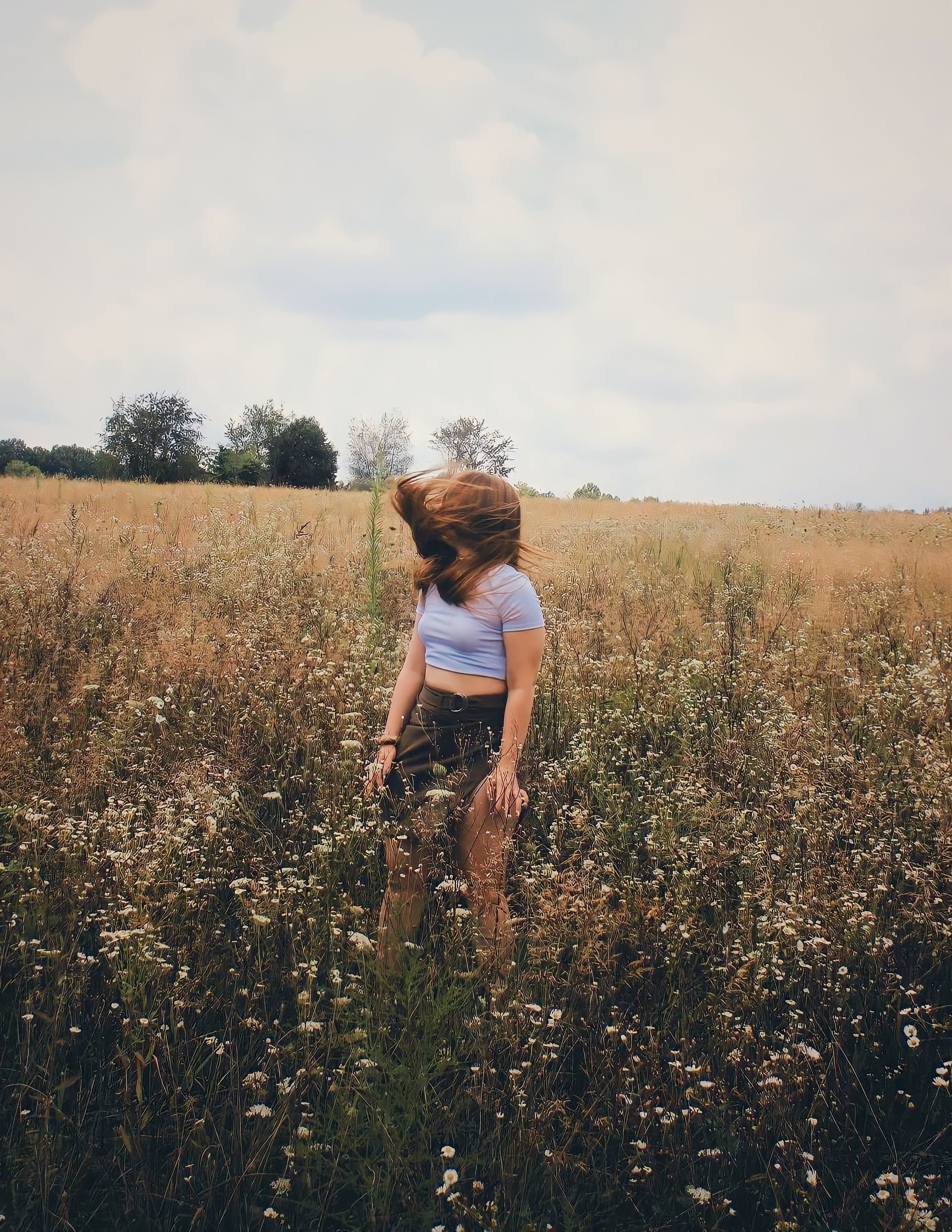 Photo of a Woman with Flowing Hair Standing in a Field · Free Stock Photo