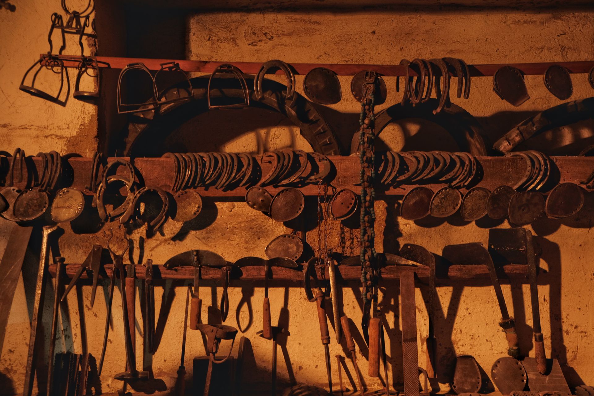 Collection of vintage horse equipment and tools displayed in a rustic barn setting.