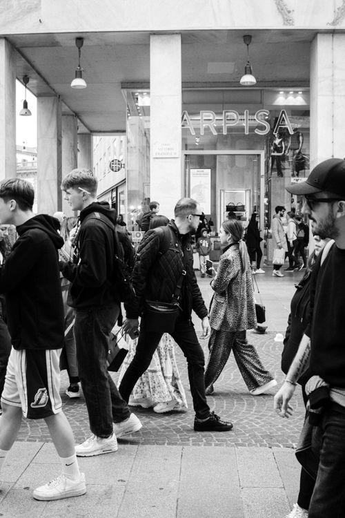 Free Black and white photo of people walking in Milan's shopping district with a storefront in the background. Stock Photo
