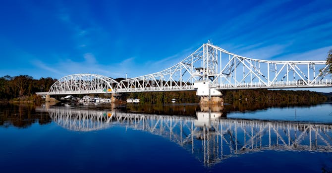 宁静的河流中倒映着优雅的白色吊桥，天空清澈