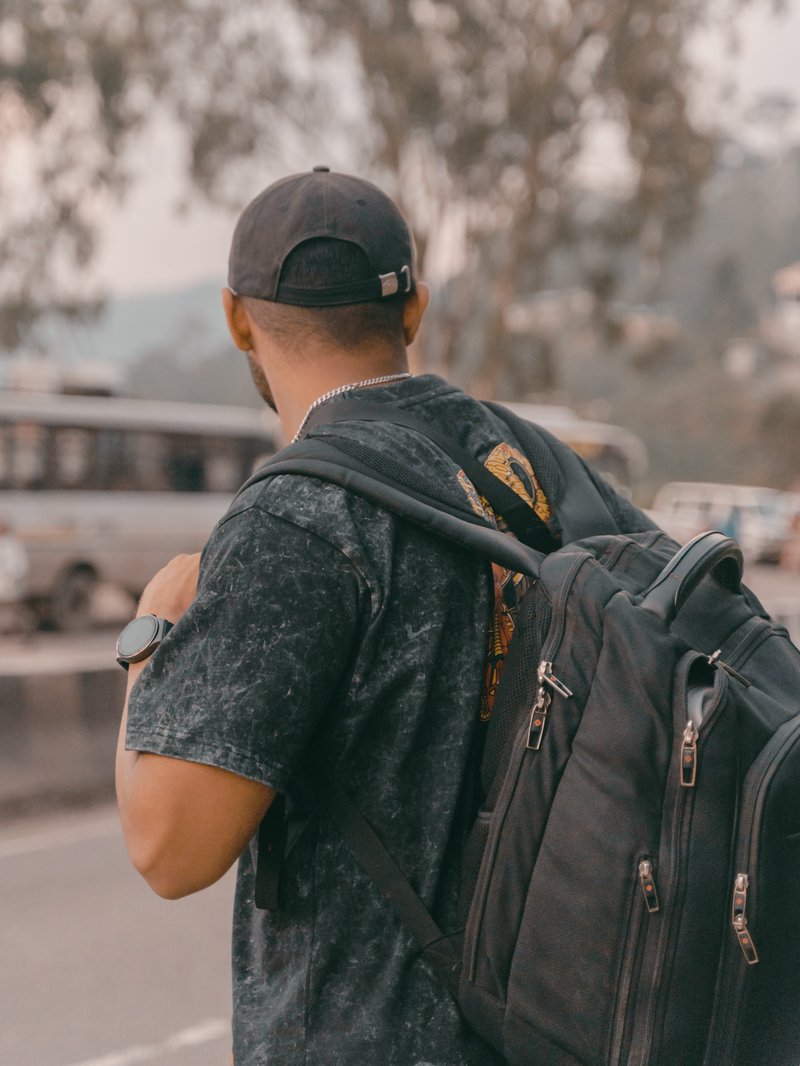 A person seen from behind carrying a dark roll-top pack — photo by Madvortex on Pexels