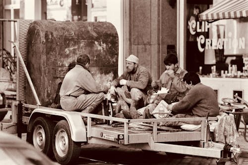 Sepia Photo of a Group of Workers Resting and Eating on a Trailer in the City