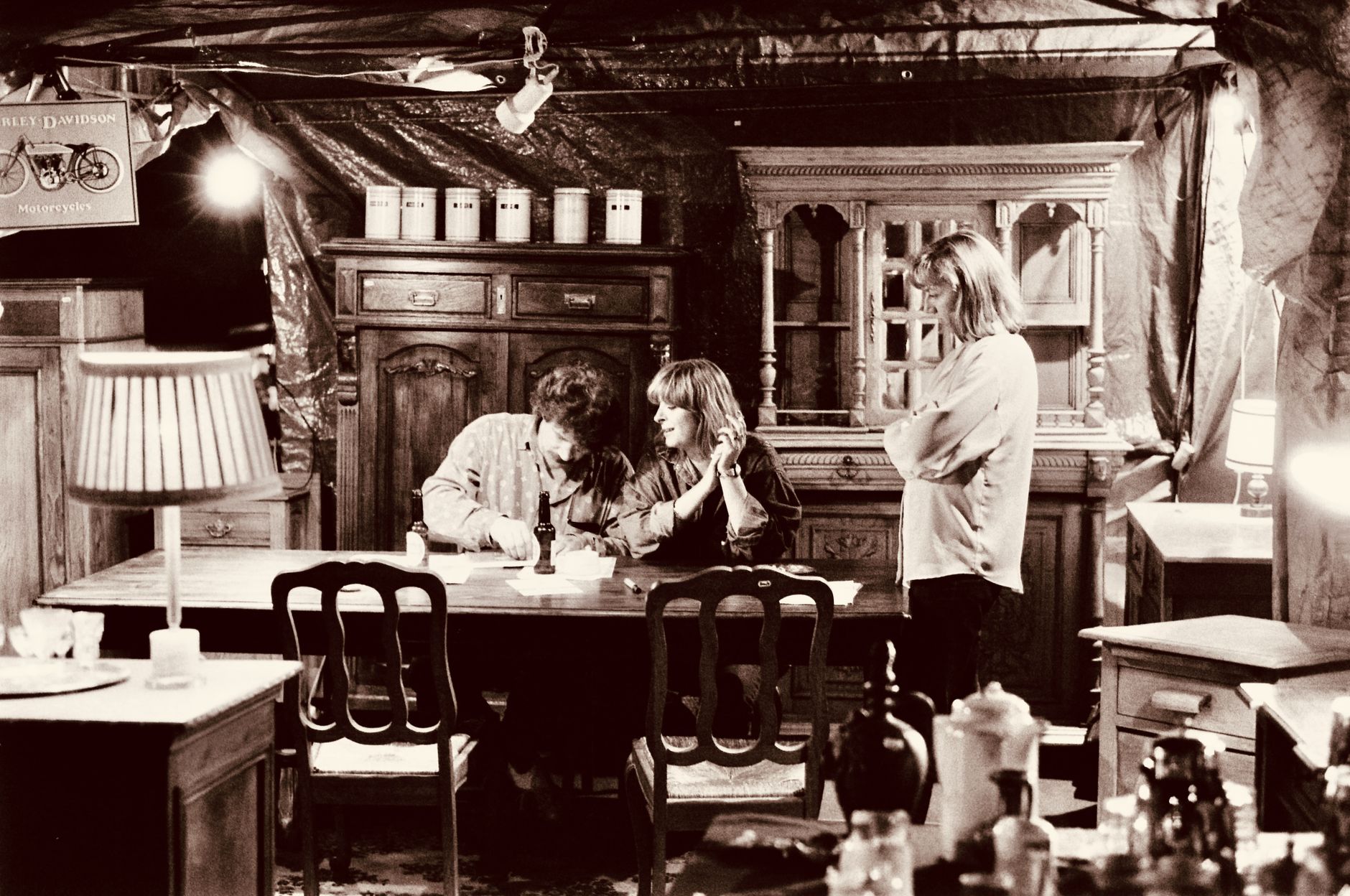 A cozy vintage dining room scene with three adults engaged in conversation.