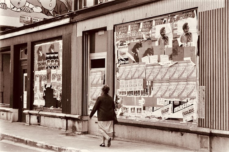 Woman Walking Near Advertisements On Building Wall