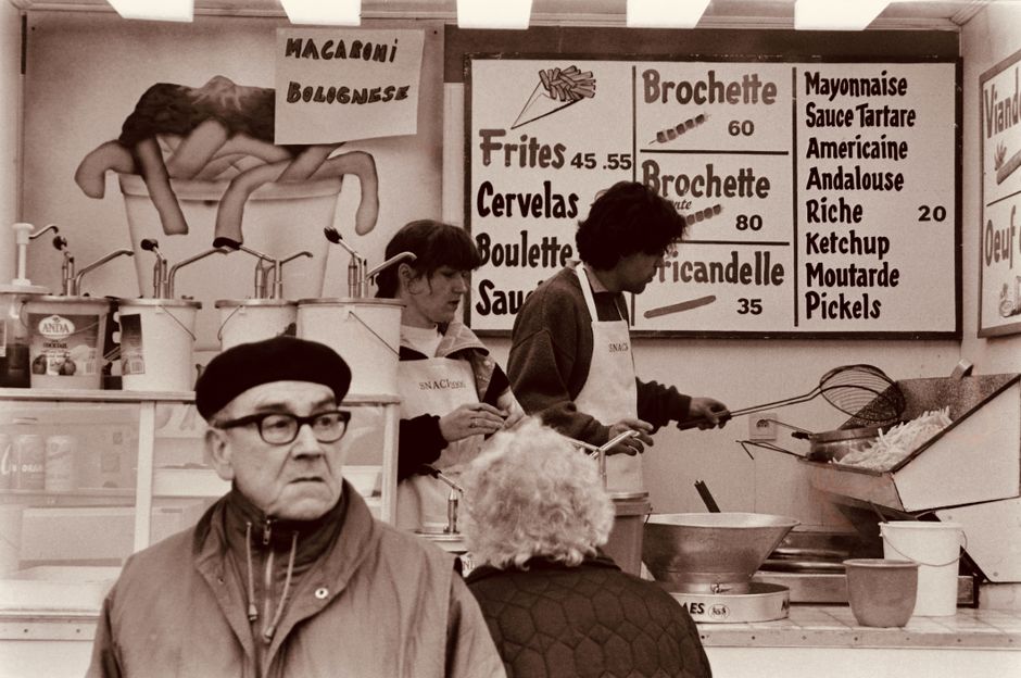 Vintage capture of a Belgian food stall with people preparing and ordering food in Nivelles.