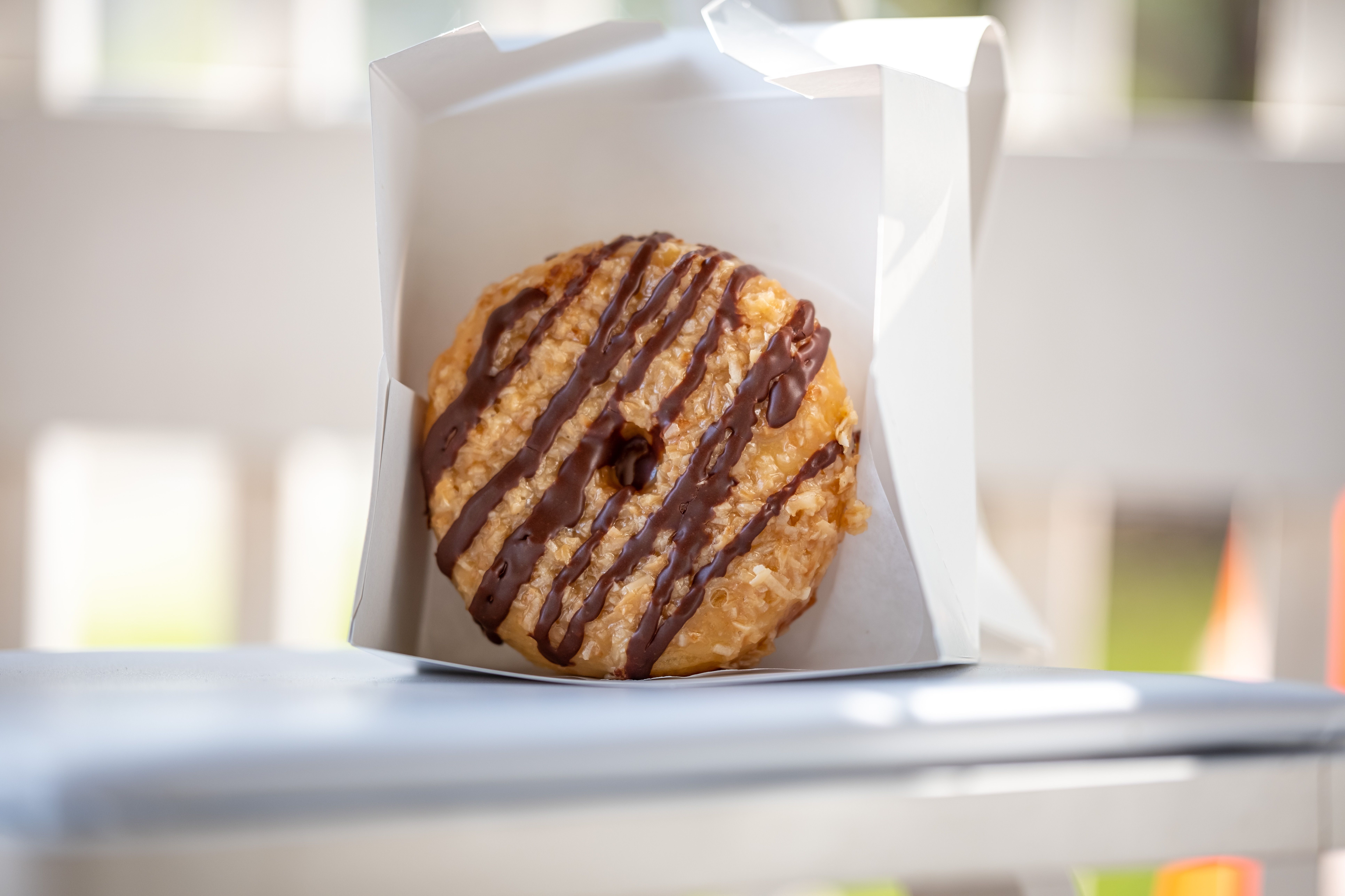A cup of coffee next to a freshly toasted bear claw donut on a plate