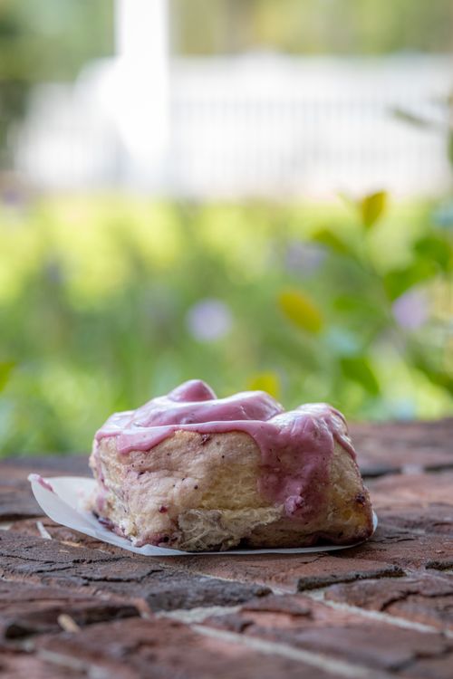 Free Close-up of a sweet roll with pink icing on a rustic brick background, outdoors. Stock Photo