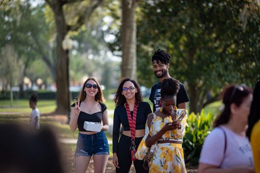 Smiling friends posing in a park on a sunny day, capturing joyful moments together.