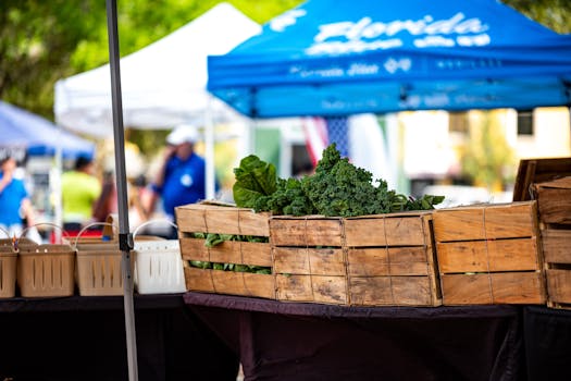 Explore a vibrant farmers' market with fresh kale and greens under blue tents.