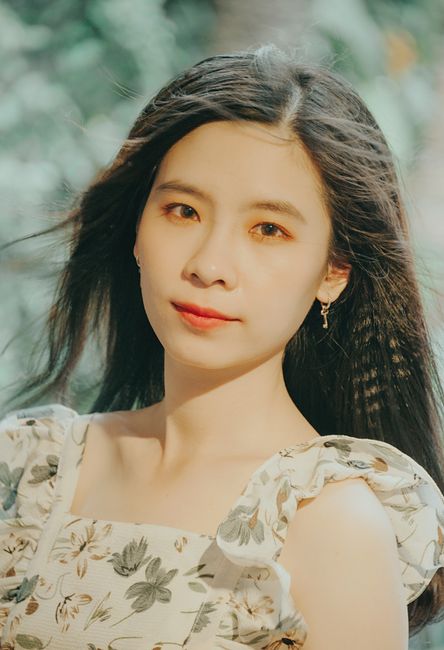 Close-up of a young woman with floral dress in a natural setting, exuding elegance and style.