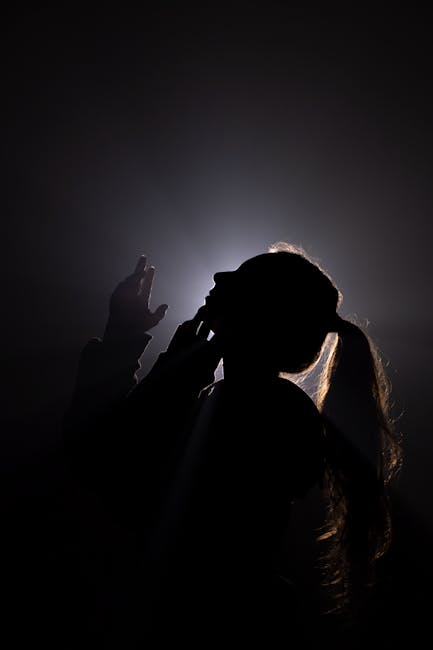 Artistic silhouette of a woman with a ponytail in dramatic backlighting.