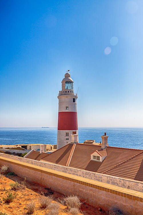 無料 海の風景写真の横にある白と赤の灯台 写真素材