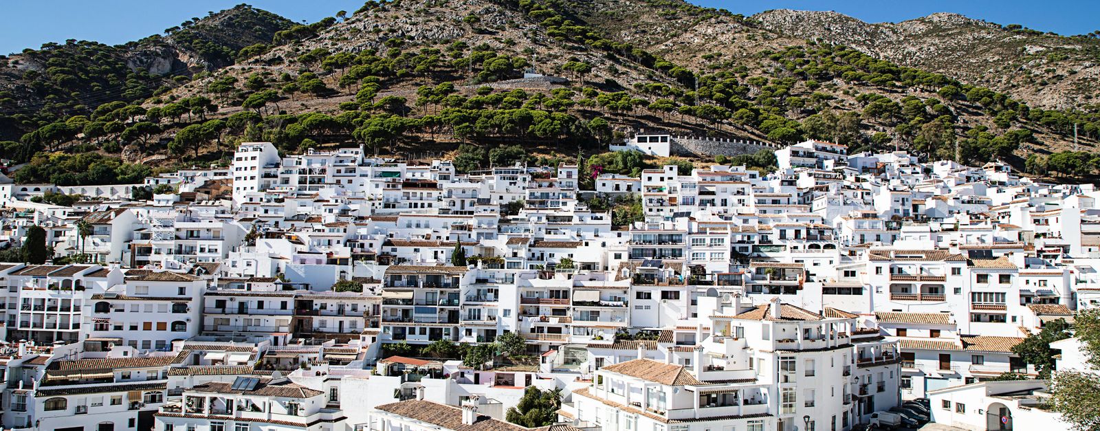 Charming view of a whitewashed Spanish town nestled in the hills during a sunny day.