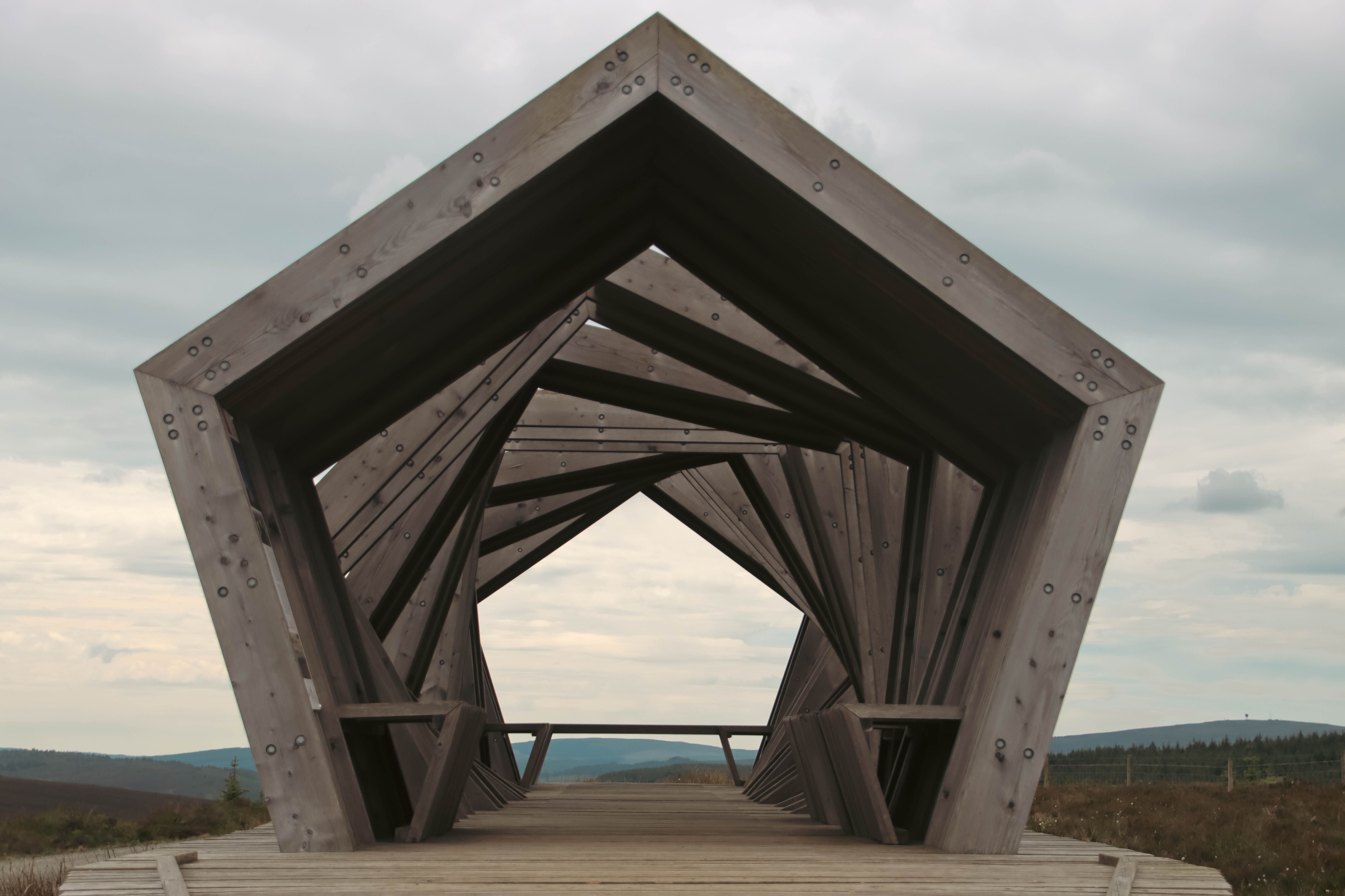 Modern wooden sculpture in Northumberland showcasing unique geometric design amidst natural landscape.