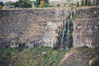 瀑布从岩崖倾泻而下，四周环绕着郁郁葱葱的植被