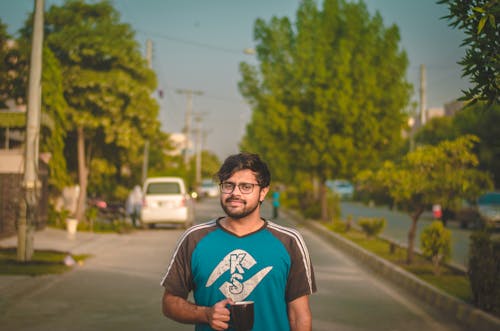 Man Standing on Road While Holding Black Ceramic Mug