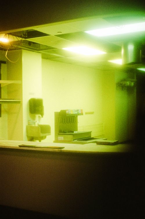 Free A haunting view of an abandoned restaurant interior featuring a soft drink machine and dim lighting. Stock Photo