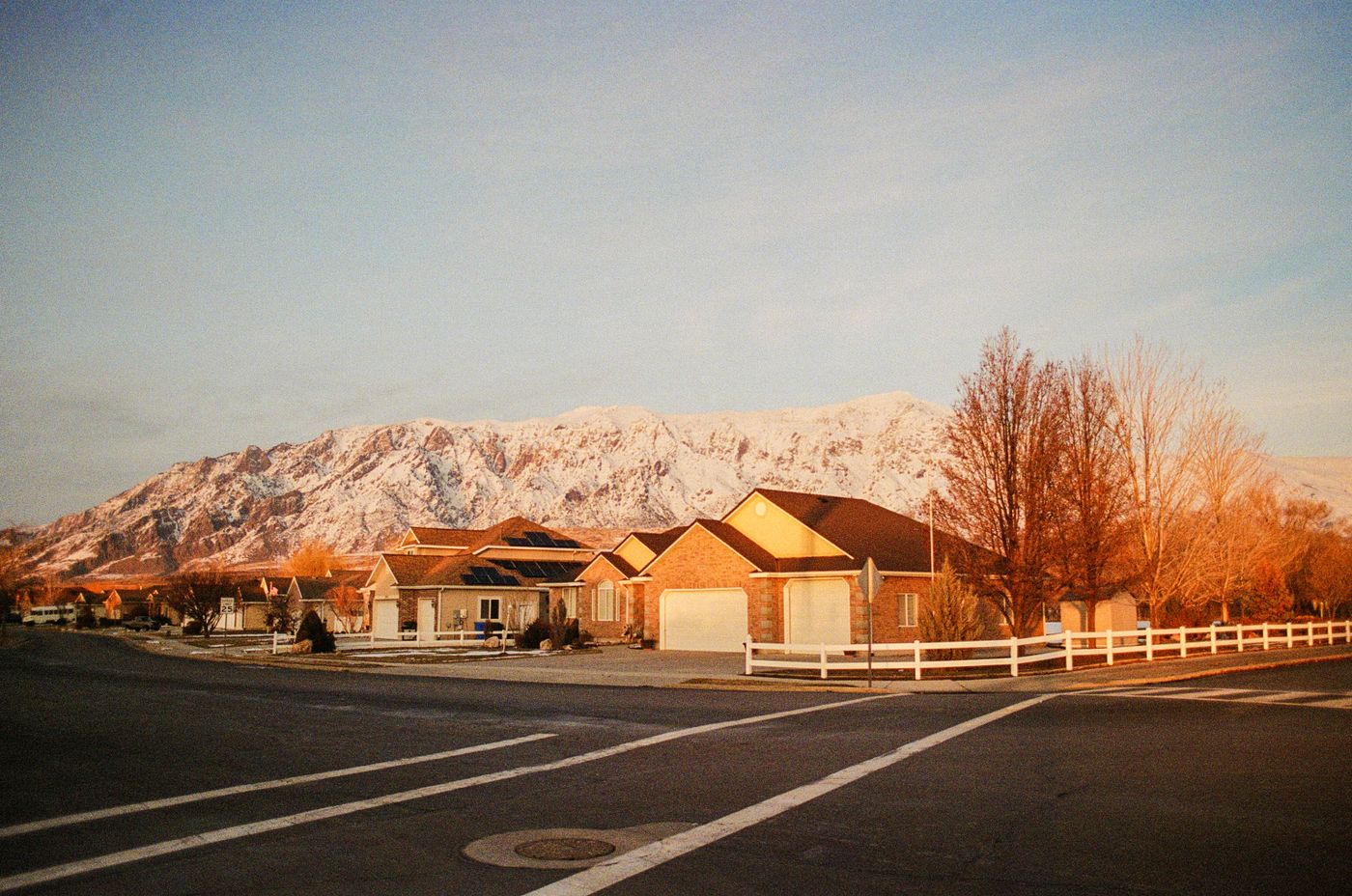 Quiet suburban street with homes and a mountain range at sunrise in winter