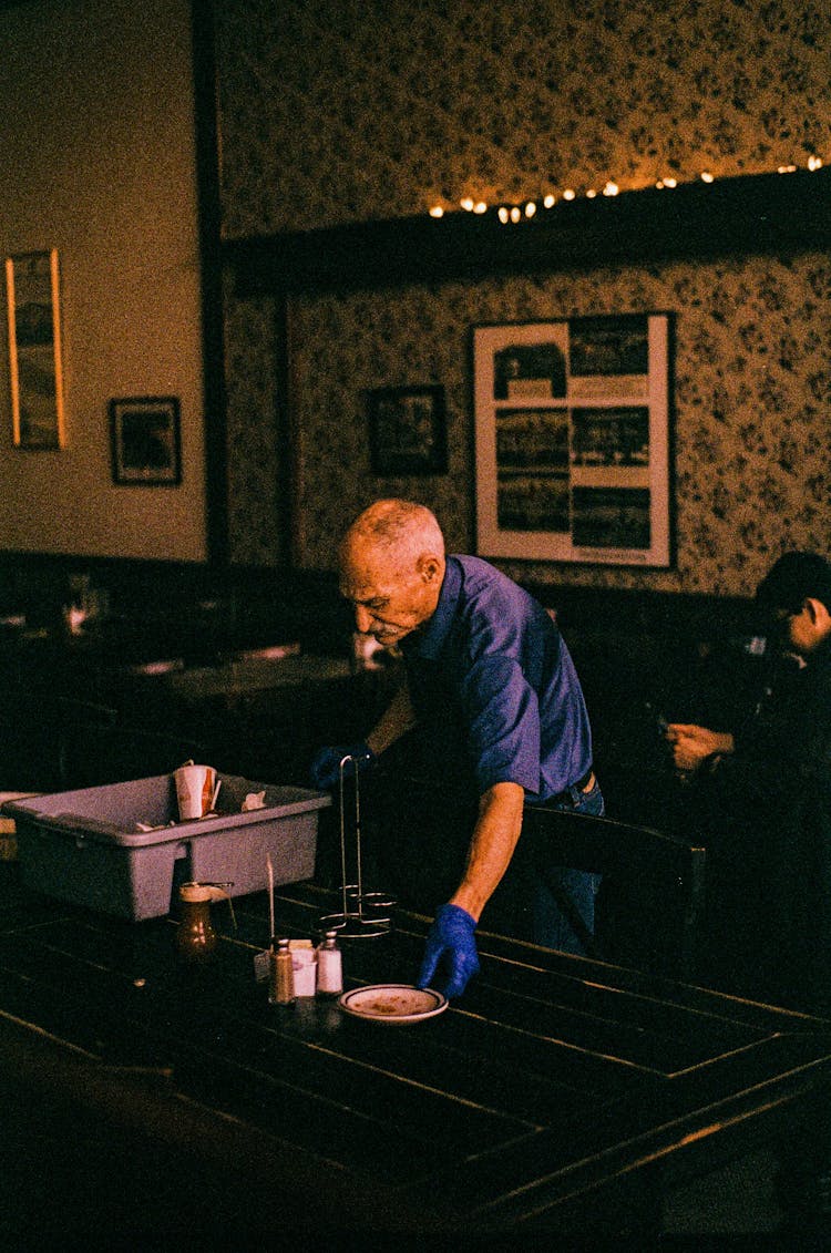 Man Cleaning Table In Restaurant