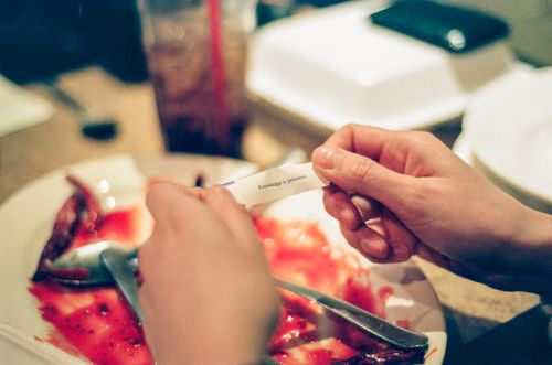 Free Hands holding a fortune cookie message over a dining table setting in a restaurant. Stock Photo