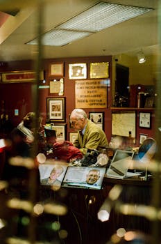 A man assisting a customer in a shop, surrounded by certificates and photos.