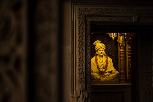 Free Serene Hindu statue embellished with garlands, housed in an intricately carved Indian temple interior. Stock Photo
