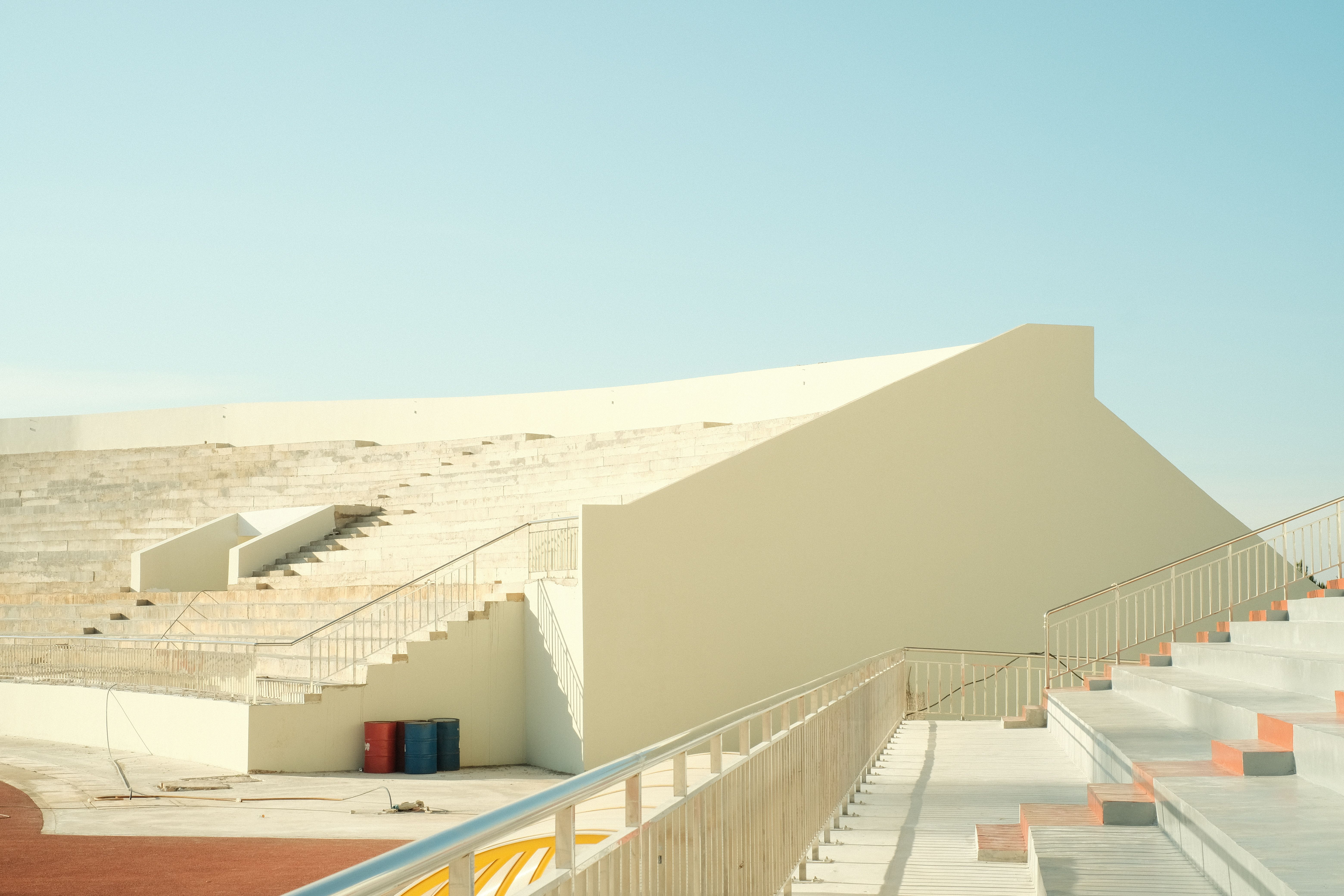 Minimalistic view of a modern empty stadium seating with clear blue sky.