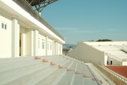 Free Empty sunlit stadium with clear blue sky and concrete seating. Stock Photo