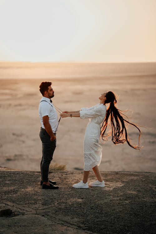Couple in Shirt and White Dress on Sea Shore at Sunset