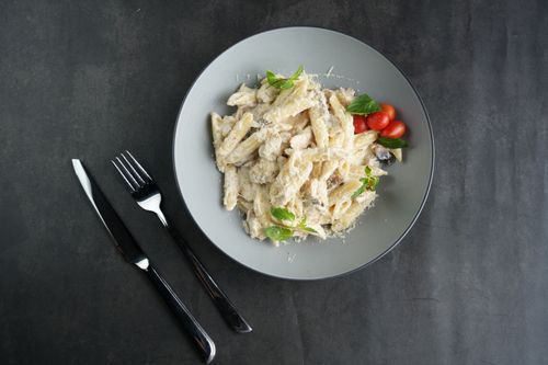 Free Creamy pasta served with fresh basil and cherry tomatoes on a modern plate. Stock Photo