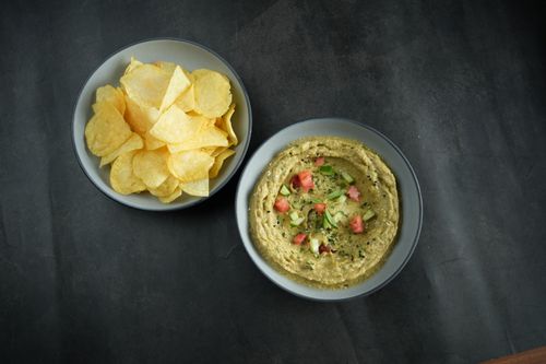 Free A tempting top view of guacamole with diced vegetables and chips on a dark surface. Stock Photo