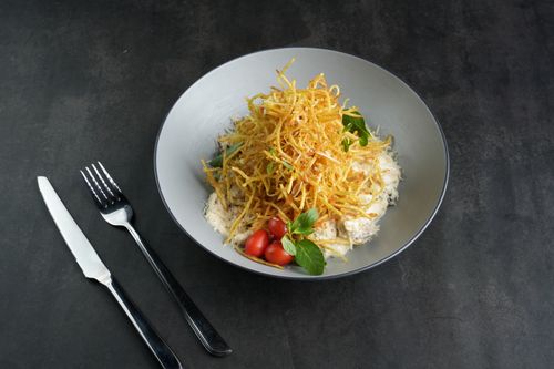 Free Elegant gourmet dish with crispy potato garnish, cherry tomatoes, and fresh basil. Stock Photo