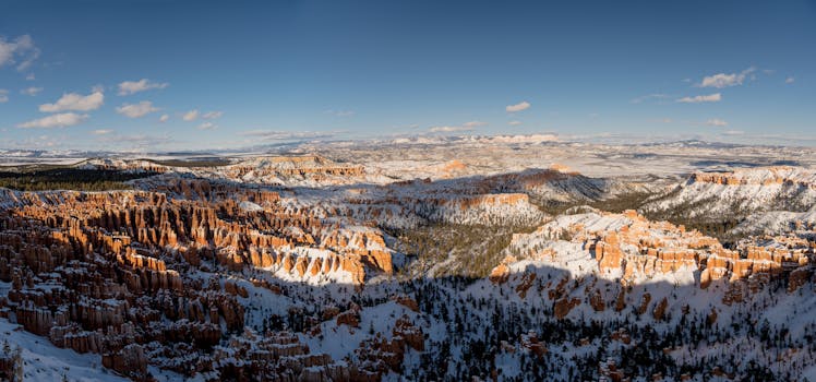 Stunning panoramic view of Bryce Canyon in winter with snow-covered hoodoos and clear blue skies.