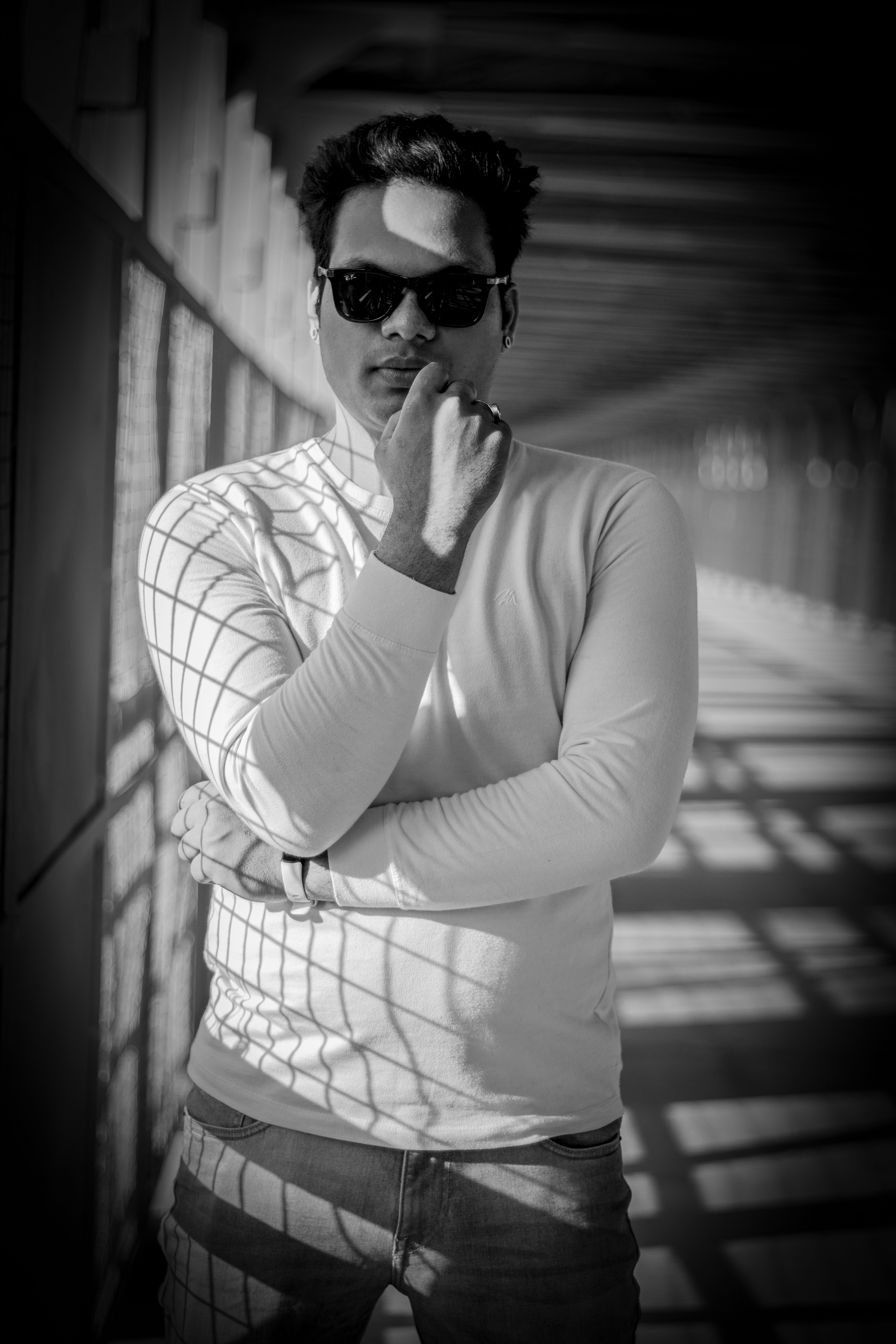 Black and white photo of a stylish man posing in sunglasses with dramatic shadows.