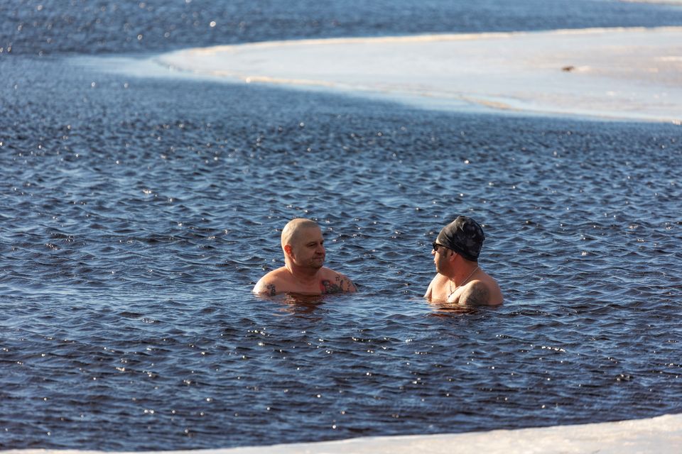 Schwimmer in einem Neoprenanzug betritt kaltes Wintermeer